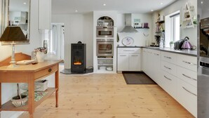 A modern kitchen with white cabinets, a central stove, and built-in ovens. - "Makrina" - 175m from the sea by Interhome (Jægerspris)