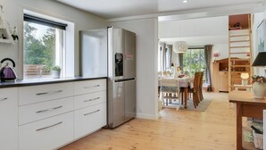 A modern kitchen with white cabinets, a stainless steel refrigerator, and a window overlooking a garden. - "Makrina" - 175m from the sea by Interhome (Jægerspris)