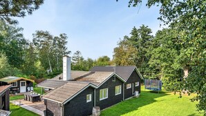 A dark wooden house with a sloped roof, a chimney, and a fenced backyard with a trampoline. - "Makrina" - 175m from the sea by Interhome (Jægerspris)
