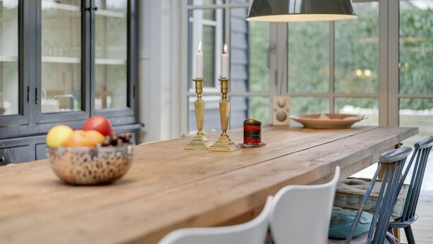 A wooden dining table with a bowl of fruit, two brass candlesticks, and a candle. - "Emely" - 700m from the sea by Interhome (Jægerspris)