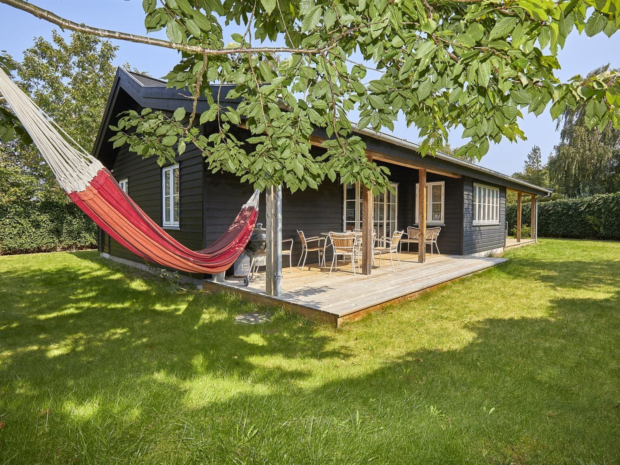 Een huis met een terras, een hangmat en tuinmeubilair.