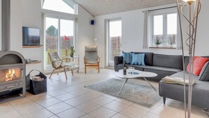 Un salon moderne avec une cheminée, un canapé gris, une table basse et un lampadaire.