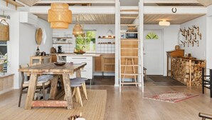 Une cuisine spacieuse avec un plafond haut, des poutres en bois et un îlot central.