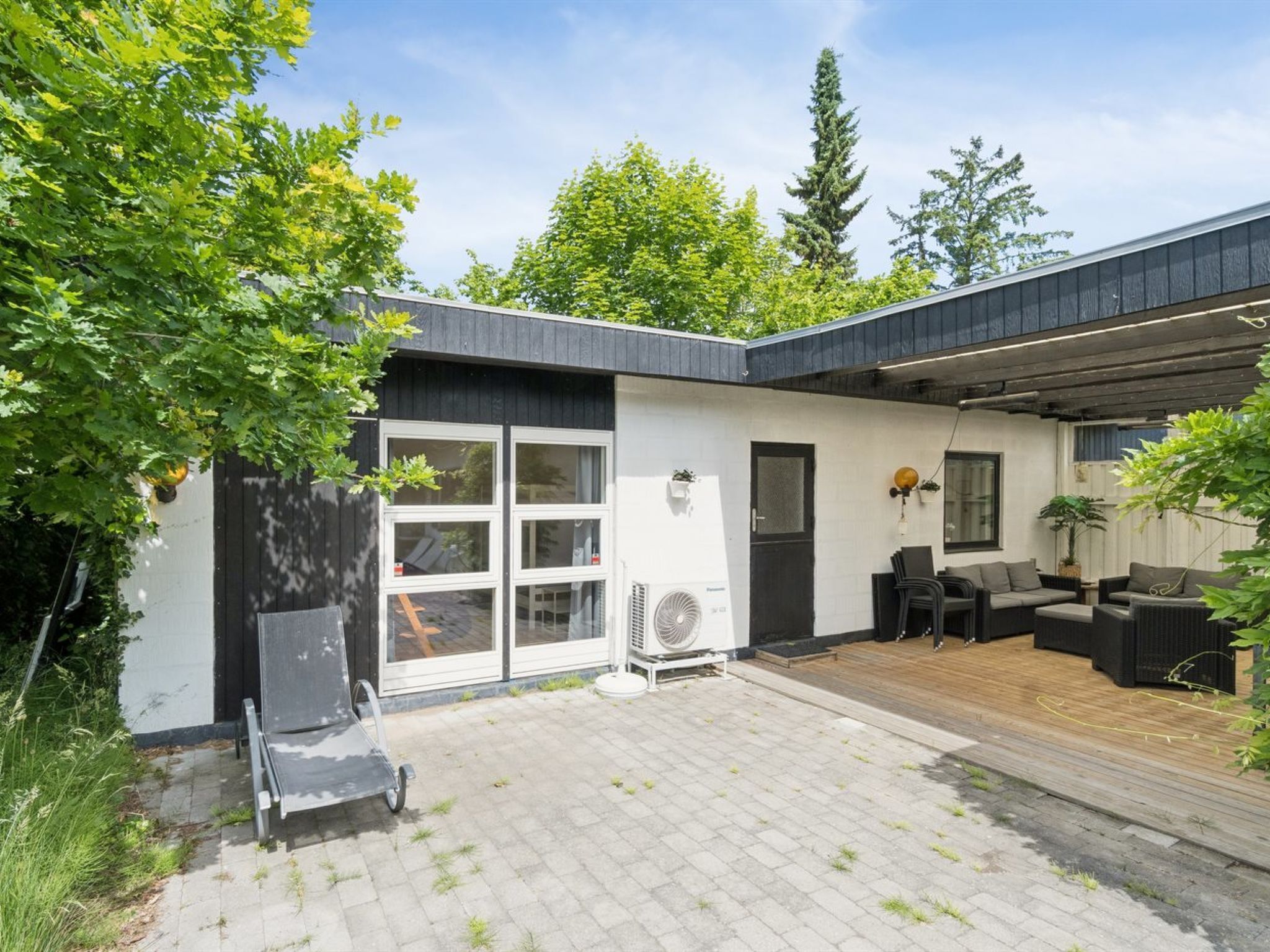 A modern house with a covered patio, a sliding glass door, and outdoor furniture.