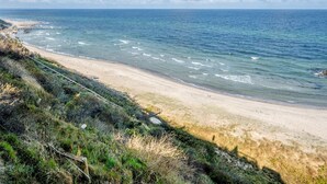 Une plage côtière avec un rivage sablonneux et une vue dégagée sur l’océan.