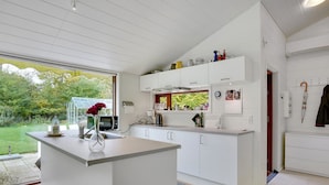 Eine moderne Küche mit weißen Schränken, einer zentralen Kochinsel und Blick zum Garten.