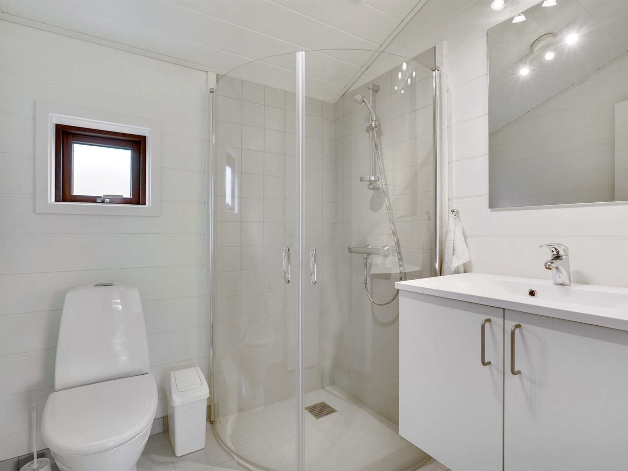 Un bagno moderno con cabina doccia in vetro, un water e un mobile lavabo con specchio.