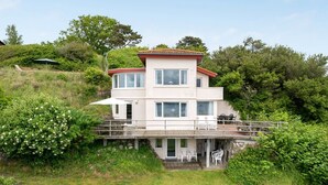 A two-story house with a balcony, surrounded by greenery. - "Grumme" - 30m to the fjord by Interhome (Ølsted)