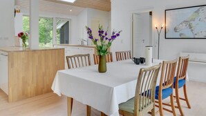 Un espace repas moderne avec un îlot en bois, une nappe blanche et des chaises.