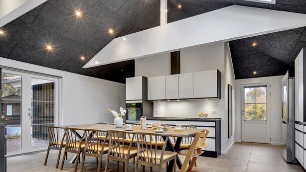 A modern kitchen with white cabinets, a central island, and a dining area with wooden chairs. - "Ribanna" - 650m from the sea by Interhome (Gilleleje)