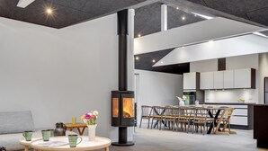 A modern living room with a central fireplace, a dining area, and a kitchen with white cabinets. - "Ribanna" - 650m from the sea by Interhome (Gilleleje)