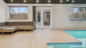 A modern indoor pool area with a built-in bench, large windows, and a ceiling with recessed lighting. - "Ribanna" - 650m from the sea by Interhome (Gilleleje)
