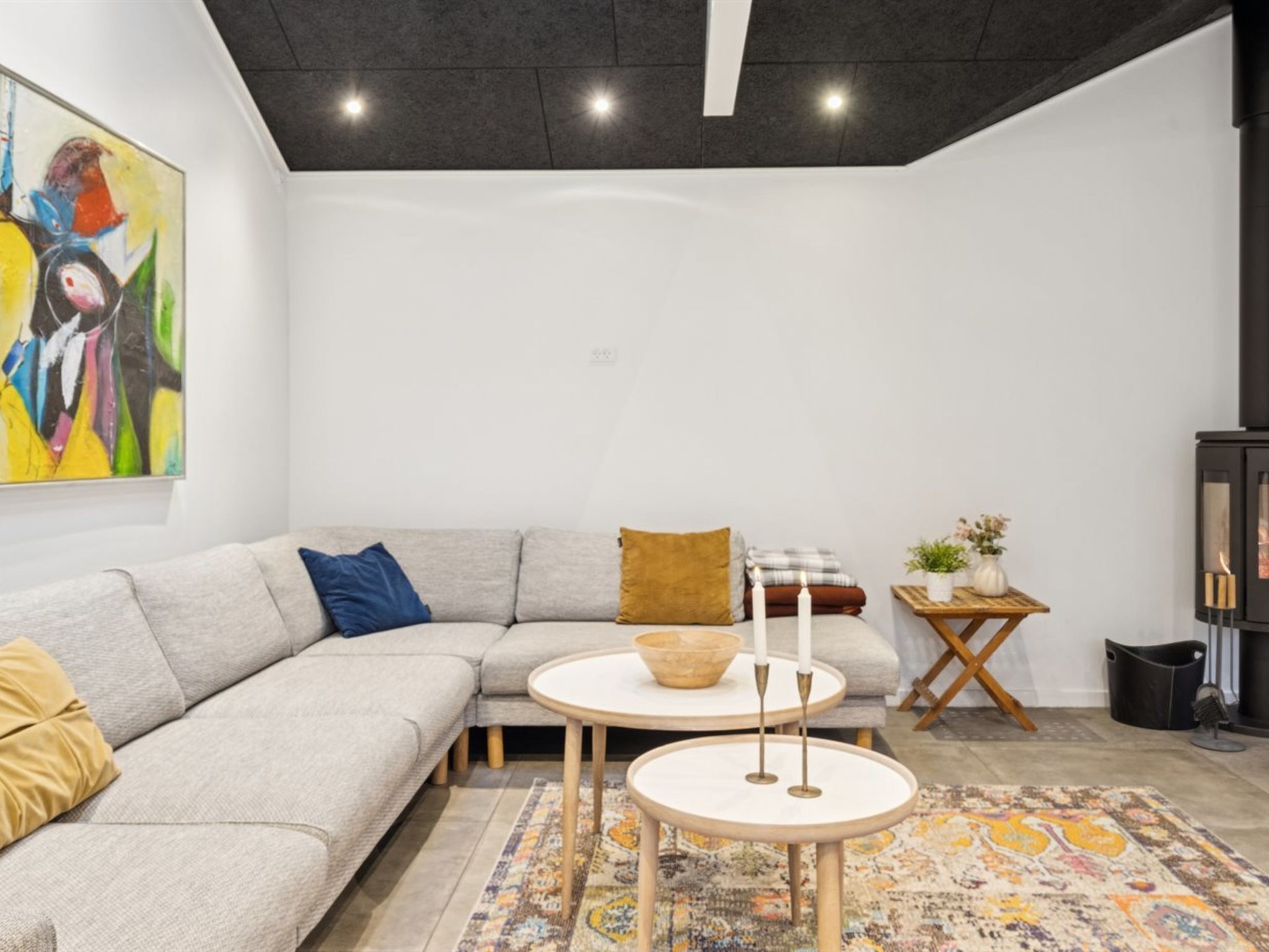A modern living room with a grey sectional sofa, a round coffee table, and a patterned rug.