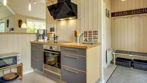 Eine moderne Küche mit Holzvertäfelung, einem Einbauofen und einer Kaffeemaschine.