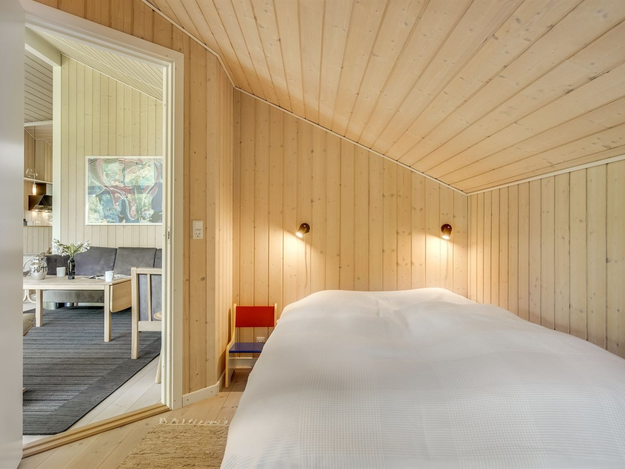 Une chambre moderne avec un grand lit, des murs en bois et un petit coin salon.