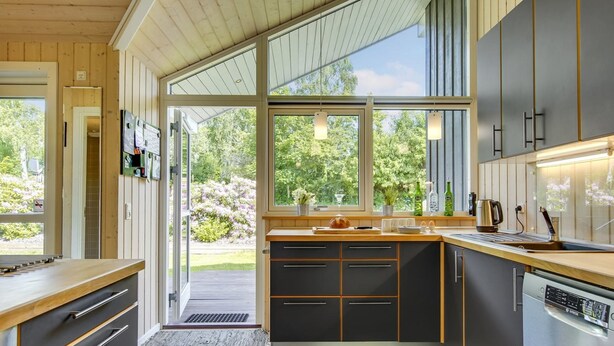 Eine moderne Küche mit einem großen Fenster, Holzschränken und einem eingebauten Geschirrspüler.