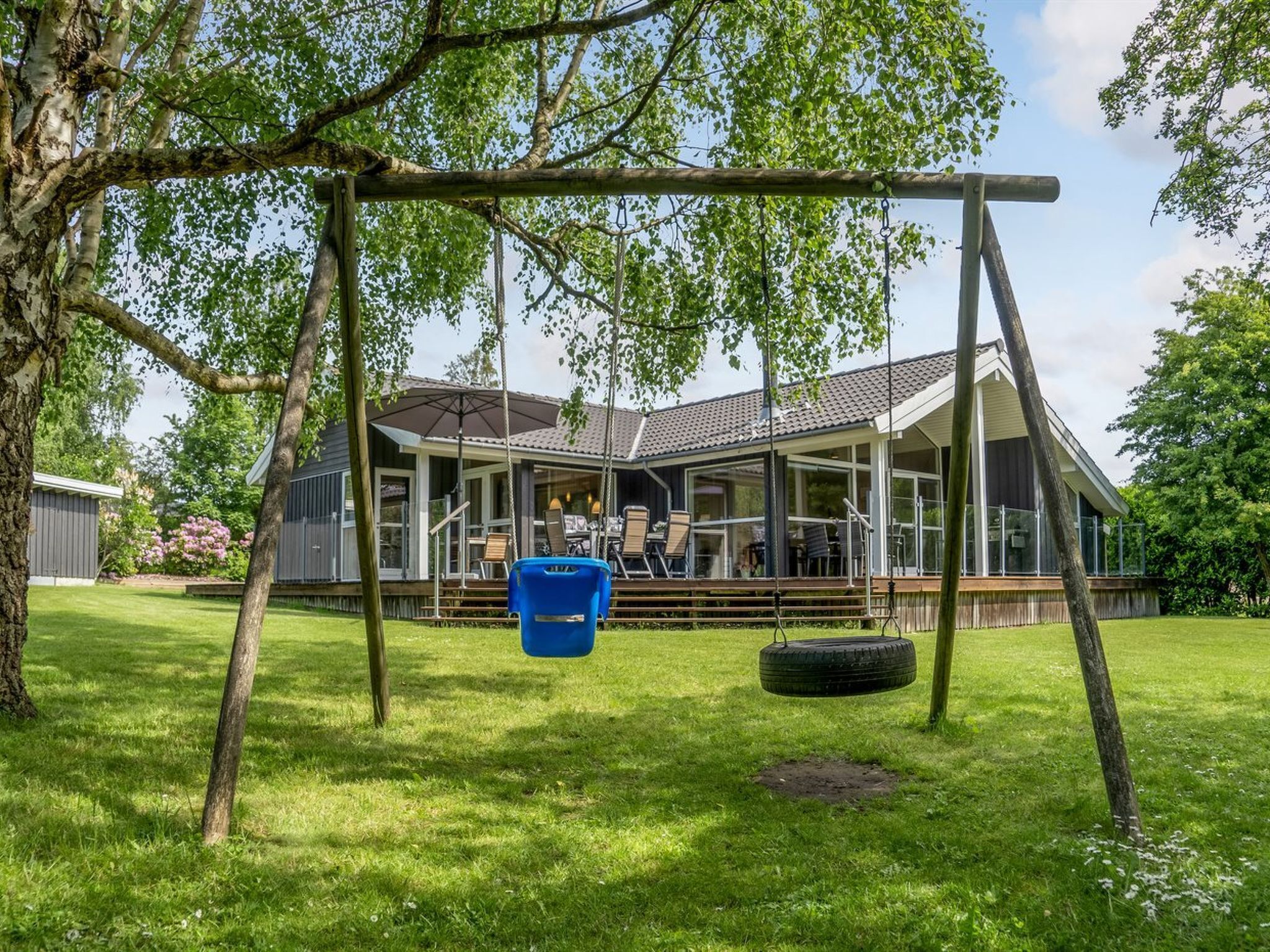 A house with a covered porch, a swing set, and a tire swing.