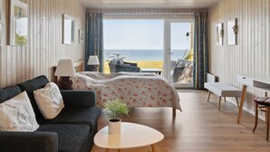 Ein gemütliches Zimmer mit einem Bett, einem Sofa, einem kleinen Tisch und Meerblick.