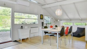 A spacious dining area with a high ceiling, large windows, and a modern chandelier.