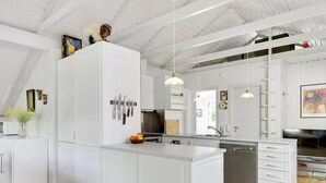 A modern kitchen with white cabinetry, a central island, and a dining area with a TV.