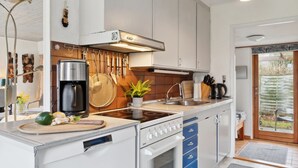 A modern kitchen with white cabinets, a built-in stove, and a coffee maker.