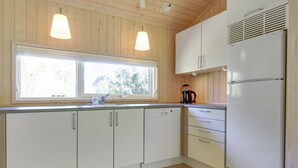 A kitchen with wooden cabinets, a white refrigerator, and pendant lights.