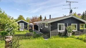A two-story cabin with a sloped roof, a satellite dish, and a picket fence.