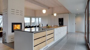 Eine moderne Küche mit einer zentralen Kochinsel, Holzschränken und einem eingebauten Kamin.