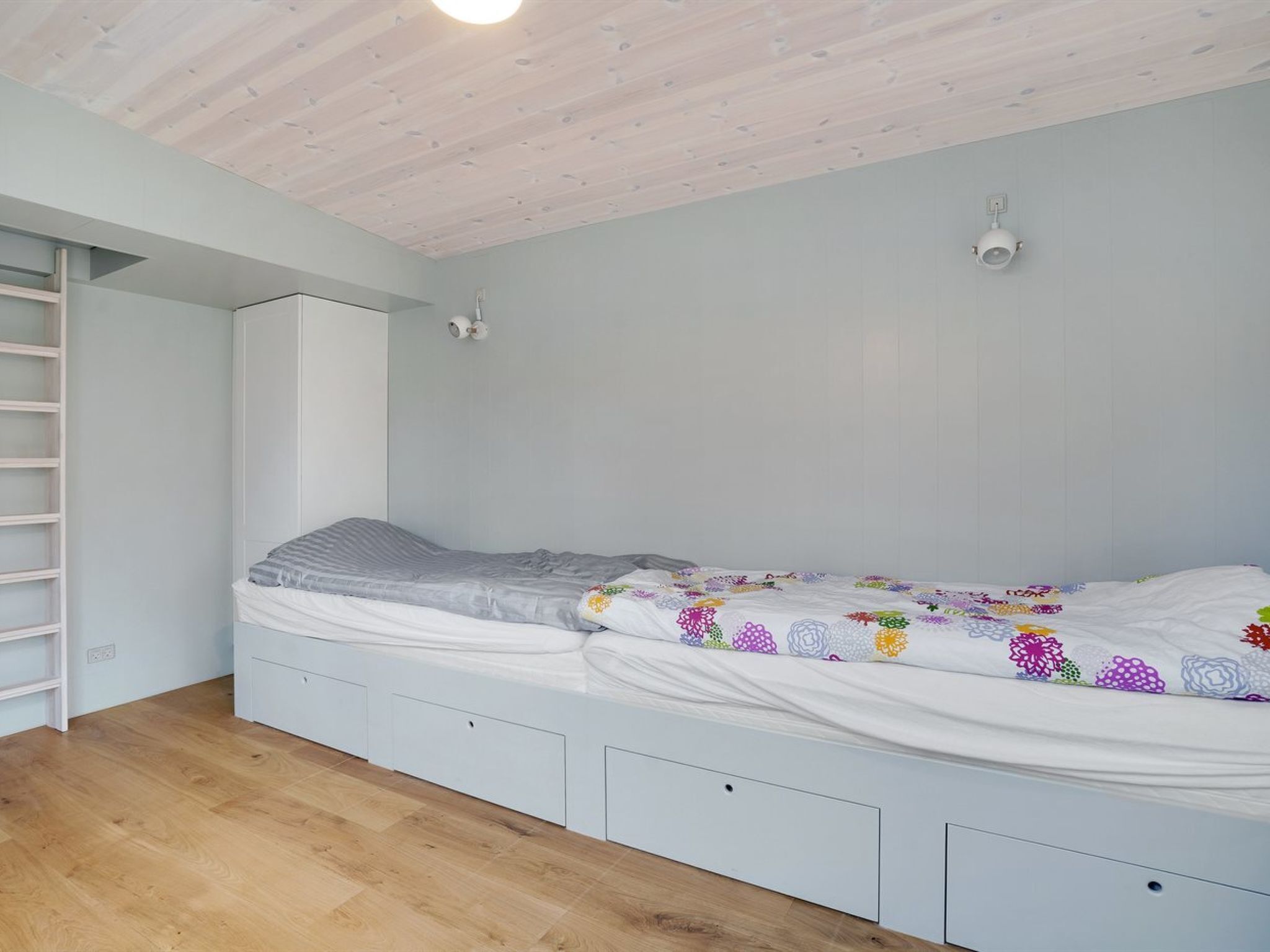 Ein Schlafzimmer mit einem Bett, Einbauschränken, einem Kleiderschrank und einer Holzbalkendecke.