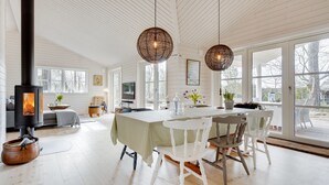 A spacious living area with a large wooden table, white chairs, and a fireplace. - "Anar" - 900m from the sea by Interhome (Græsted)