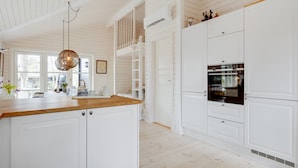 A spacious kitchen with white cabinetry, a wooden countertop, and a built-in oven. - "Anar" - 900m from the sea by Interhome (Græsted)