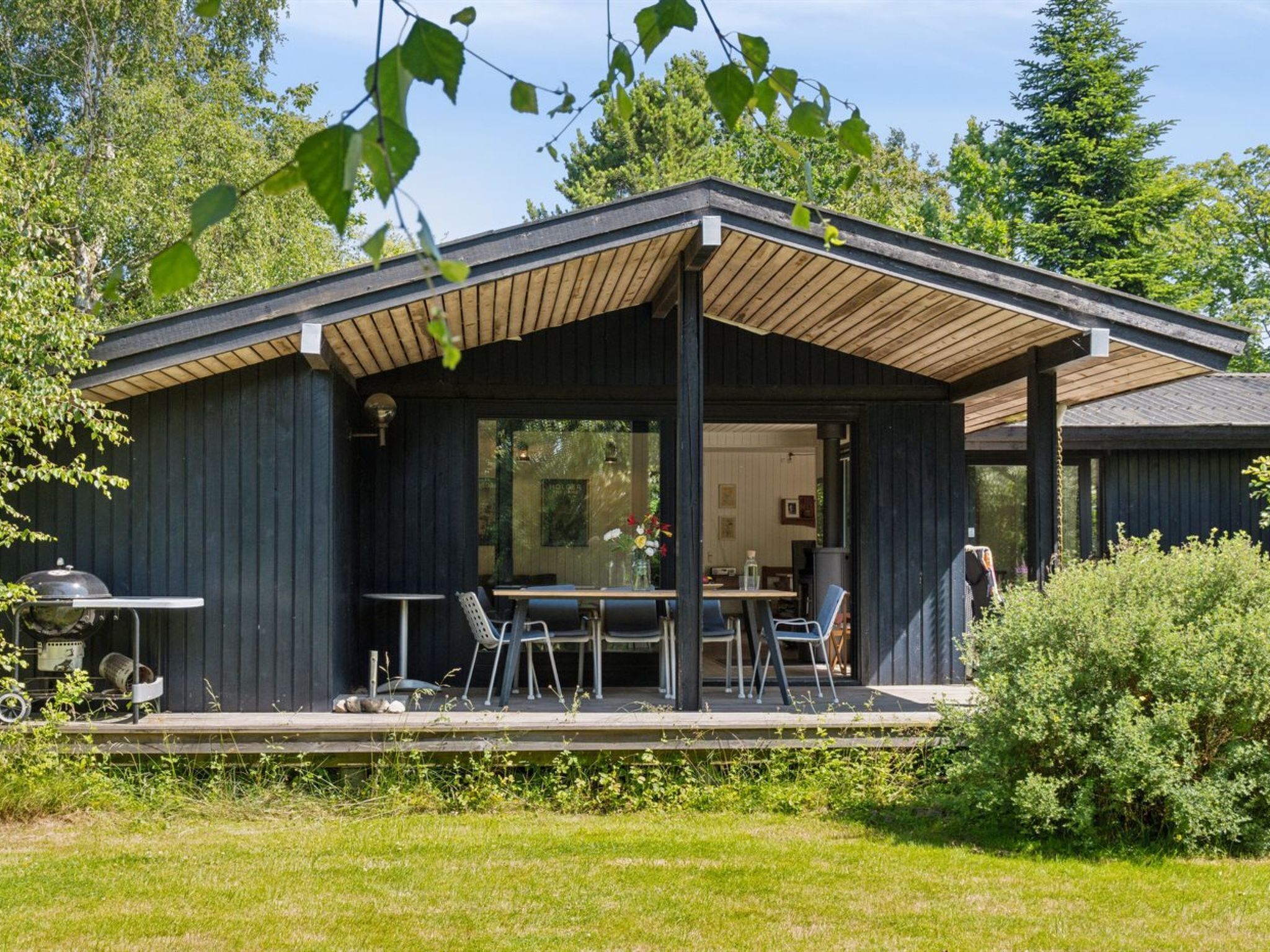 Ein moderner Essbereich im Freien mit einer Holzdielenfläche, Metallstühlen und einem Tisch.