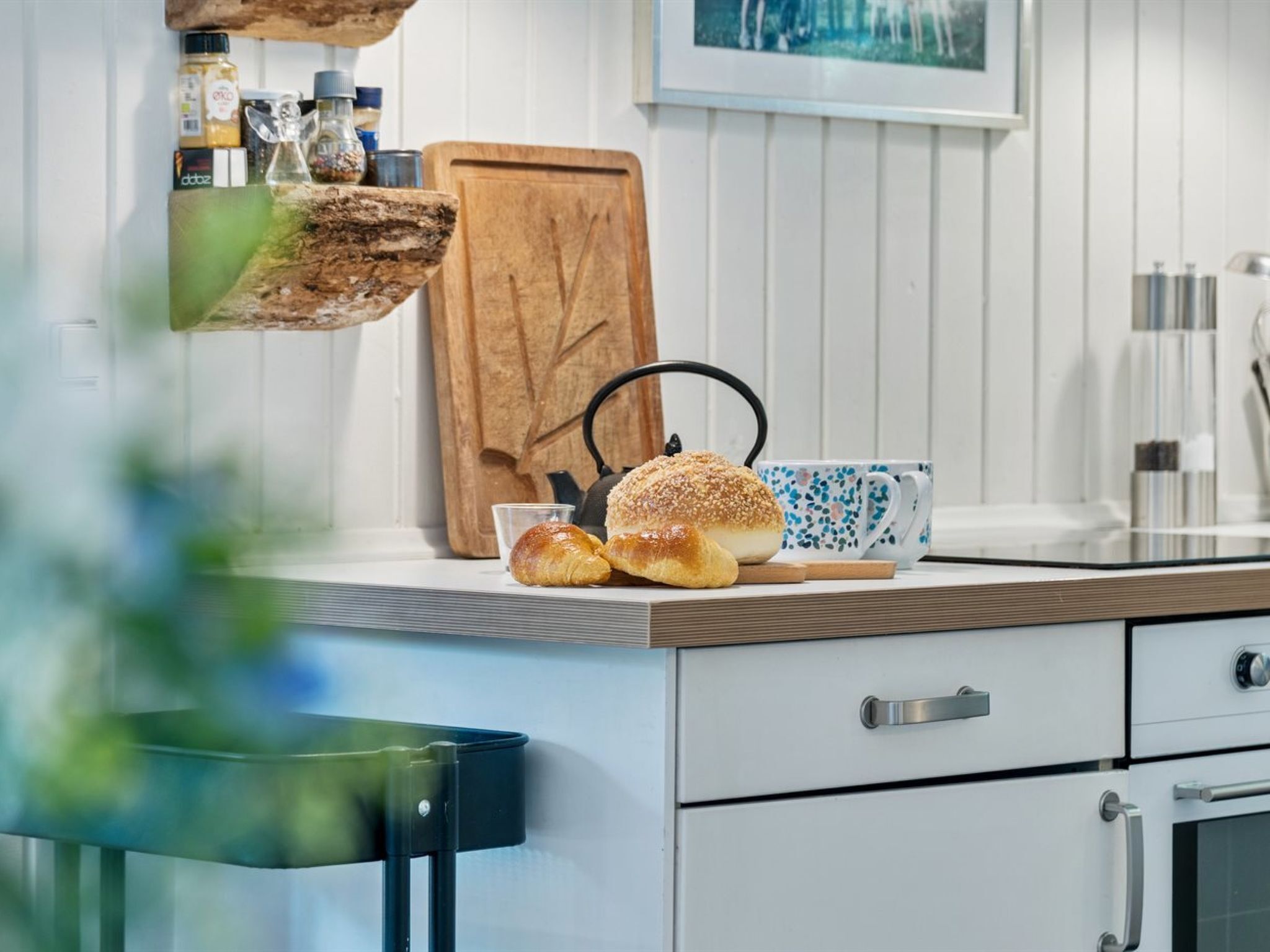 Een keukentafel met een broodmand, een theepot en een koffiemok.