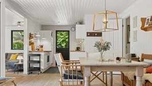 A spacious room with a wooden dining table, chairs, and a hanging light fixture.