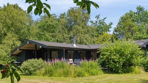 A modern house with a covered porch, surrounded by lush greenery and a well-maintained lawn.