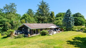 A house with a covered patio, surrounded by a grassy lawn and trees. - "Naira" - 1.8km from the sea by Interhome (Tisvildeleje)