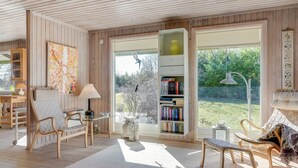 A cozy reading nook with a wooden floor, a bookshelf, a desk with a lamp, and a comfortable chair. - "Naira" - 1.8km from the sea by Interhome (Tisvildeleje)