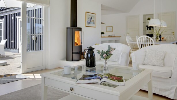 A modern living room with a wood-burning stove, white furniture, and a glass coffee table with a magazine. - "Drude" - 920m from the sea by Interhome (Vejby)