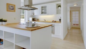 A modern kitchen with white cabinetry, a wooden island, and a stainless steel range hood. - "Drude" - 920m from the sea by Interhome (Vejby)