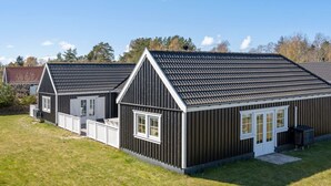 A two-story building with a dark exterior and white trim, featuring a pitched roof and multiple windows. - "Drude" - 920m from the sea by Interhome (Vejby)