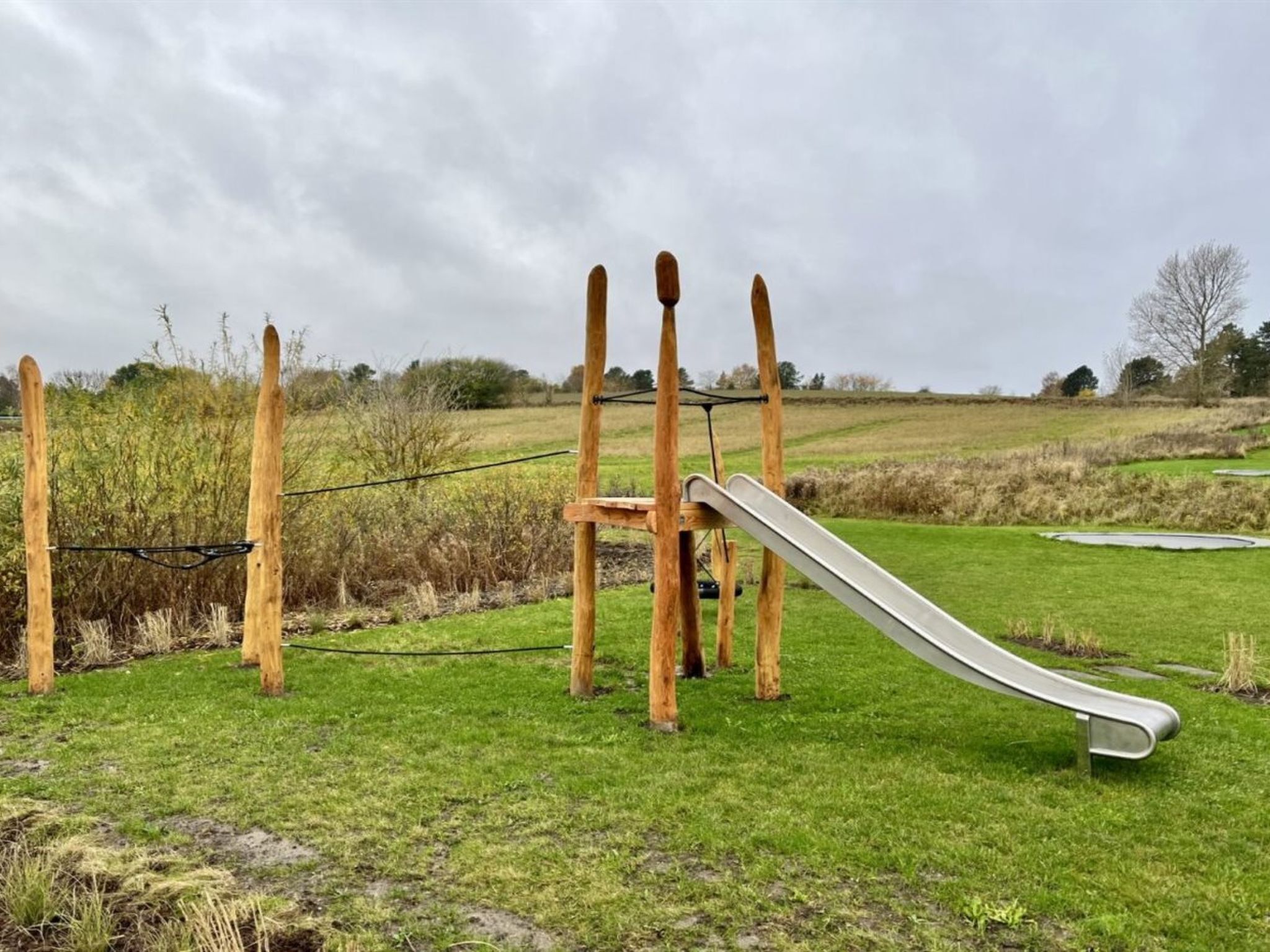 Un parque infantil con un tobogán y postes de madera.