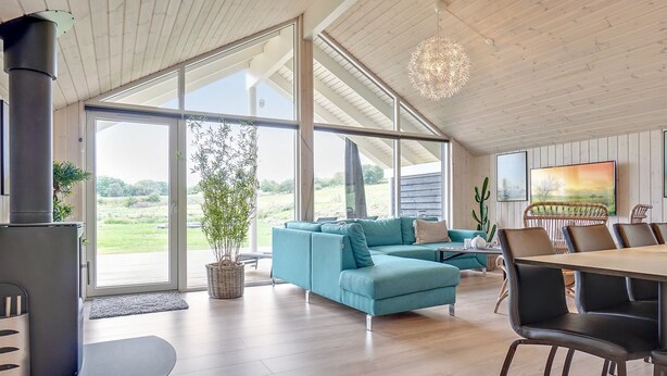 A modern living room with a sofa, dining table, chairs, and a large window offering a view of the outdoors.
