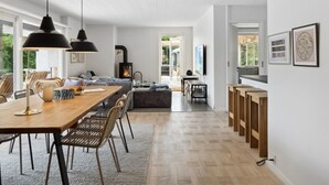A modern kitchen with a wooden dining table, chairs, and pendant lights.