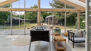 A spacious room with a large glass ceiling, a foosball table, a chess table, and a comfortable seating area.