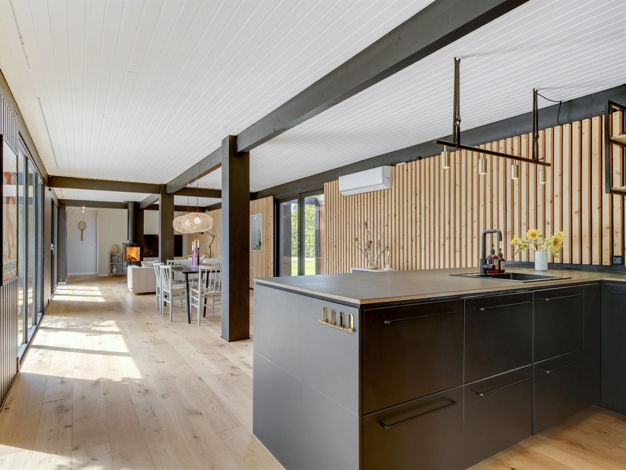 Une cuisine moderne dotée d’un grand îlot central, de touches de bois et offrant une vue sur l’extérieur.