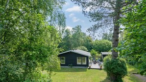 Ein abgelegenes Blockhaus mit einer Terrasse, umgeben von üppiger Vegetation und Bäumen.