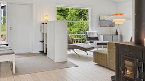 A modern living room with a fireplace, a sofa, a chair, and a dining area.