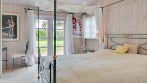 Una camera da letto con un letto a baldacchino, una sedia e un quadro appeso al muro.