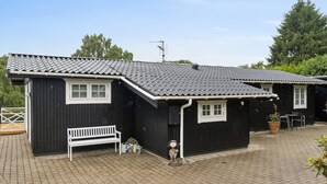 A black building with a sloped roof, a white bench, and a small garden area with a bird sculpture. - "Ylermi" - 1.5km from the sea by Interhome (Dronningmølle)