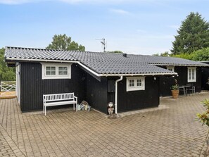 A black building with a sloped roof, a white bench, and a small garden area with a bird sculpture. - "Ylermi" - 1.5km from the sea by Interhome (Dronningmølle)